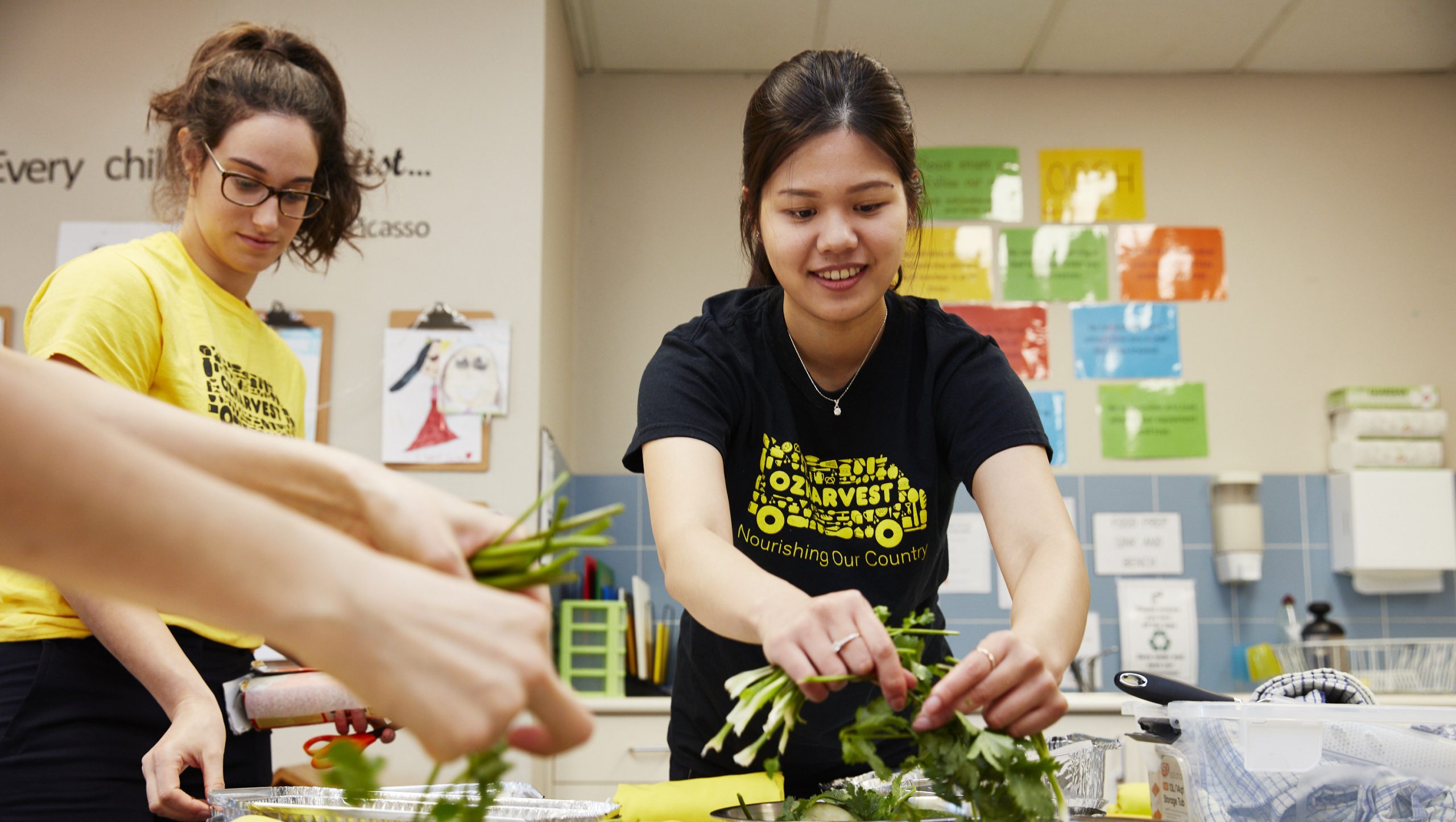 Two OzHarvest female volunteers cooking during an ozharvest education class