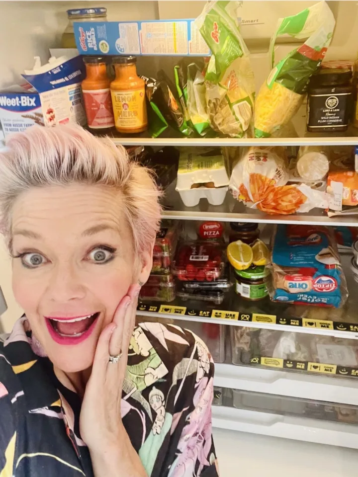 Jessica Rowe posing in front of her open fridge smiling with her hand on her cheek