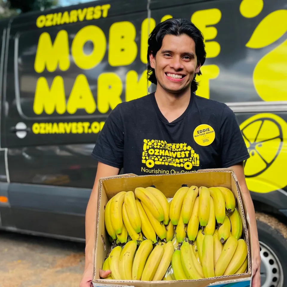 OzHarvest food rescue driver holding a box of bananas.