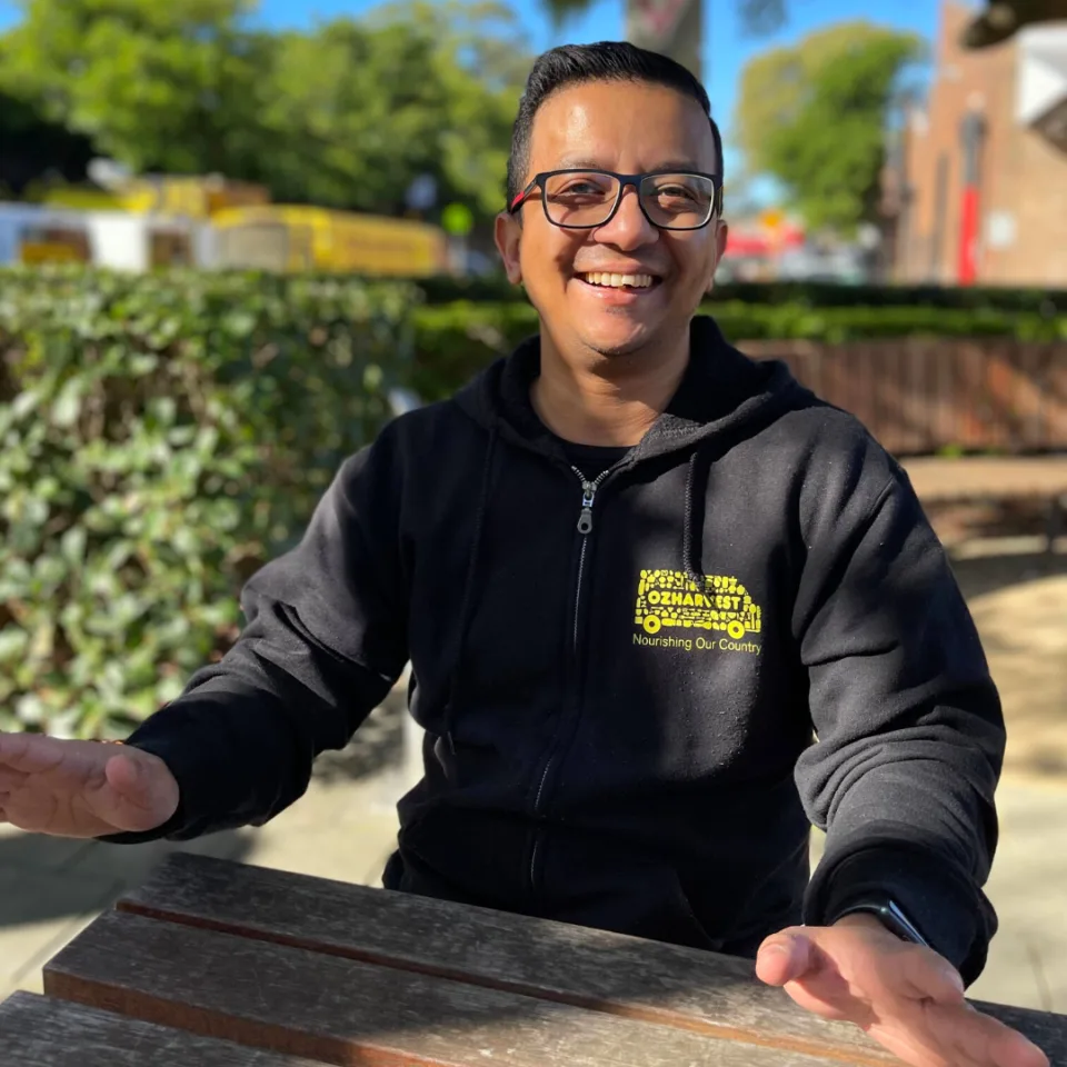 OzHarvest staff member smiling and sitting outside headquarters.