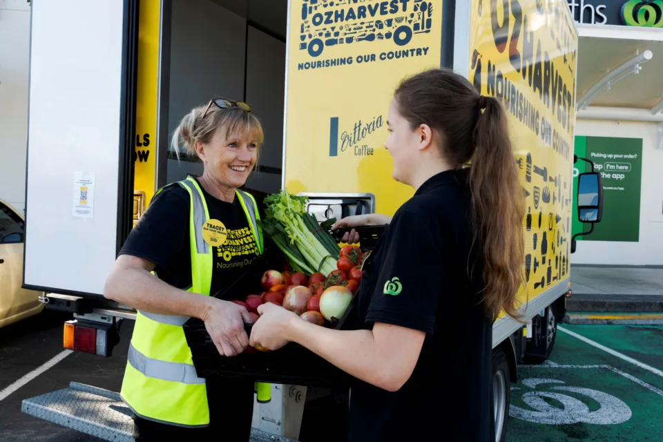 OzHarvest food rescue driver handing a crate of food to a Woolworths team member.