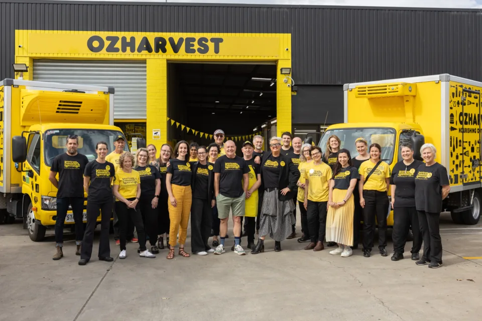 Staff wearing yellow and smiling outside OzHarvest Adelaide headquarters.